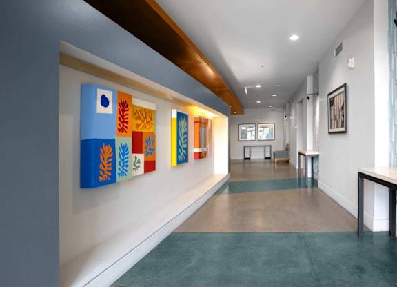 A hallway with a blue carpet and a wall with paintings on it.