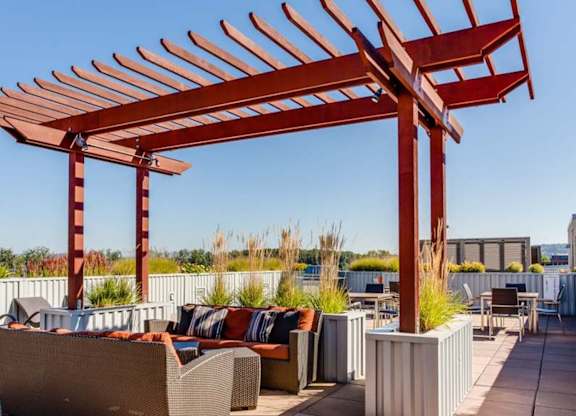 A red pergola is over a patio with couches and tables.