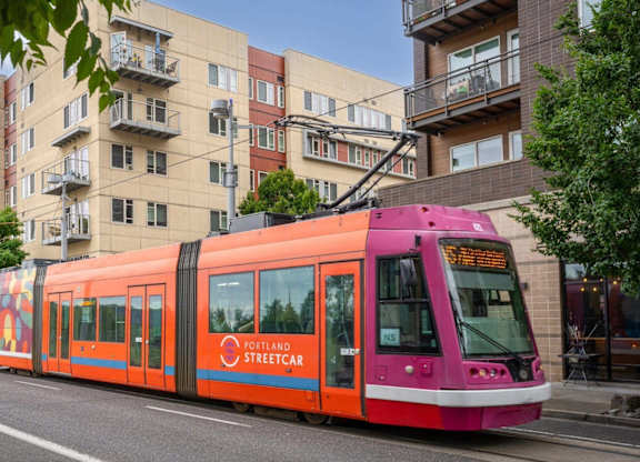 A streetcar with a pink and orange design is on a street.