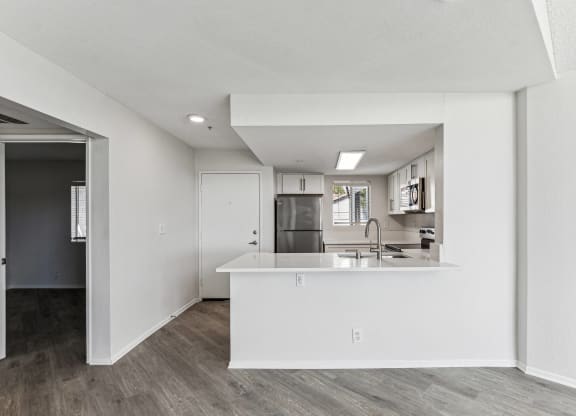 an open kitchen and living room with white walls and wood flooring