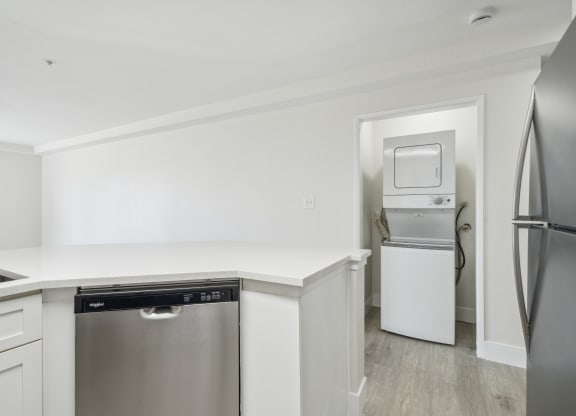 a white kitchen with stainless steel appliances and a white counter top