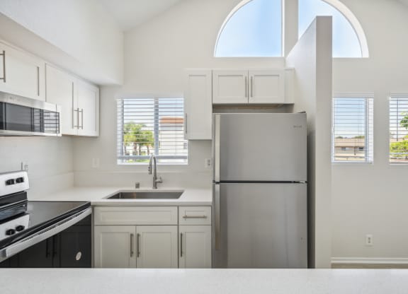 a white kitchen with a stainless steel refrigerator