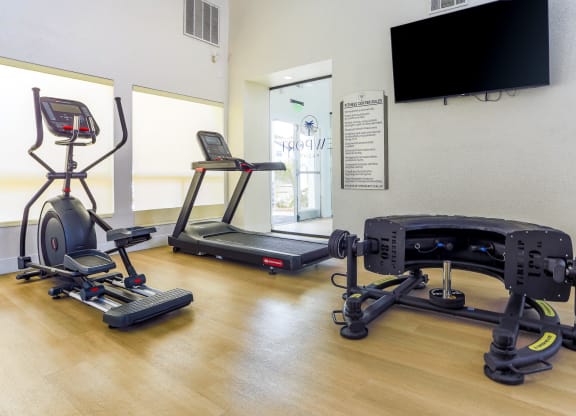 a gym with exercise equipment and a tv on the wall
