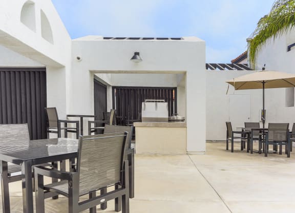 a patio with tables and chairs and an umbrella