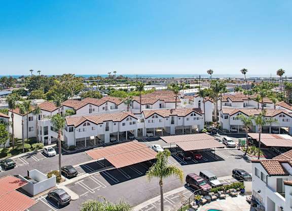 A sunny day at a residential complex with cars parked in the lot.