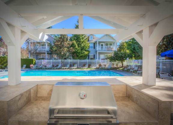 a swimming pool with a hot tub and a pool house in the background