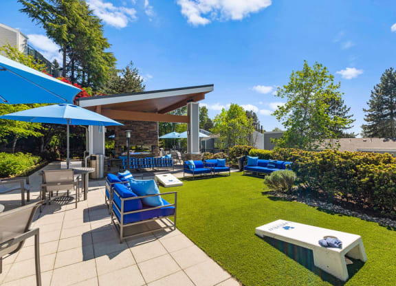 a patio with blue chairs and umbrellas and a lawn