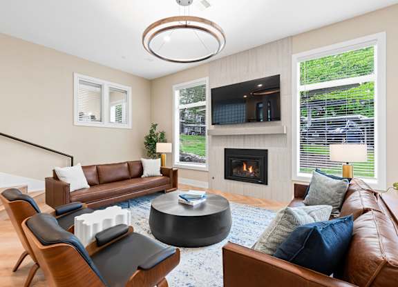 A living room with a brown leather couch, a fireplace, and a television.