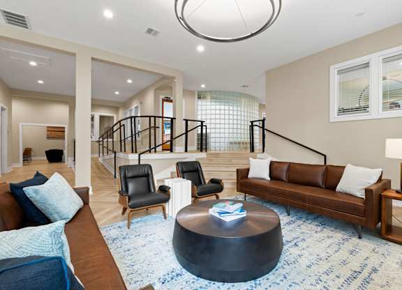 A living room with a brown couch, a blue rug, and a black coffee table.