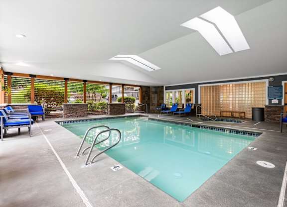 A large indoor swimming pool with a diving board and lounge chairs.