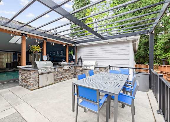 A patio with a table and chairs and a grill.