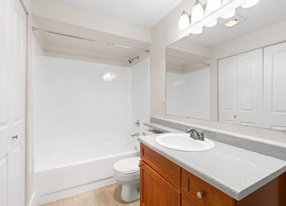 A white bathroom with a toilet, sink, and mirror.