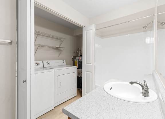 A white bathroom with a sink and a washer and dryer.