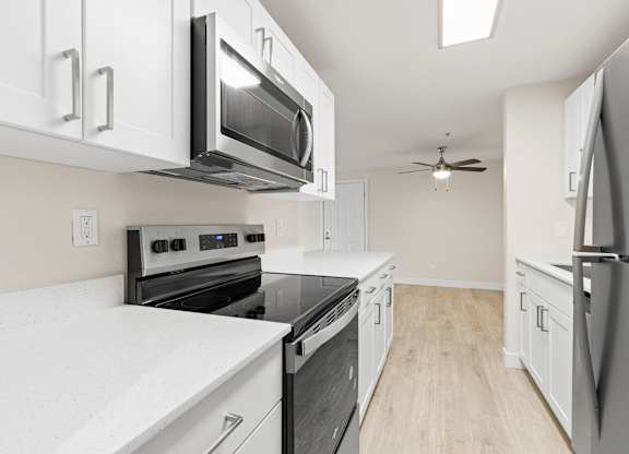 A kitchen with white cabinets and black appliances.