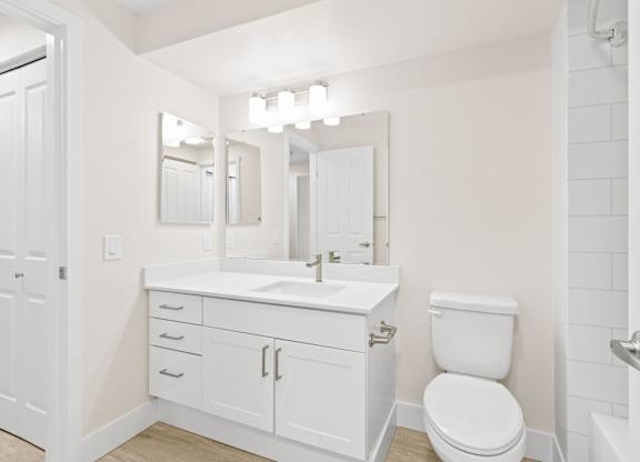 A white bathroom with a toilet, sink, and mirror.