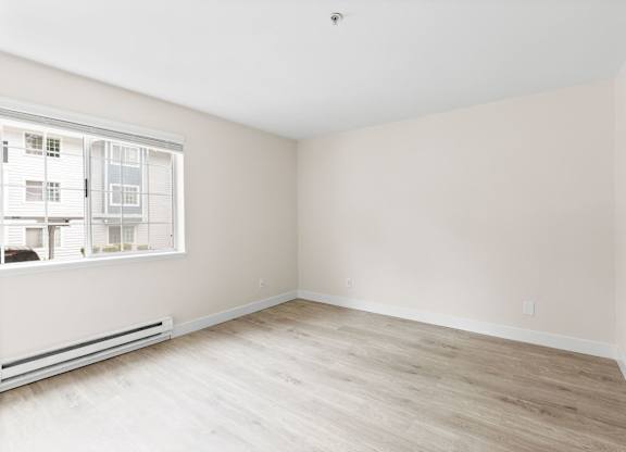 Empty room with a window and a radiator on the wall.
