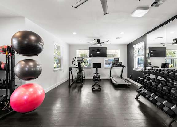 A gym with a variety of equipment including a treadmill, a rowing machine, and a stationary bike.