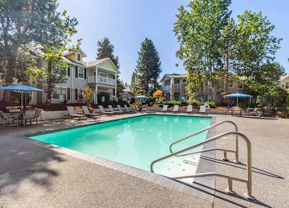 A swimming pool surrounded by a metal railing and chairs.