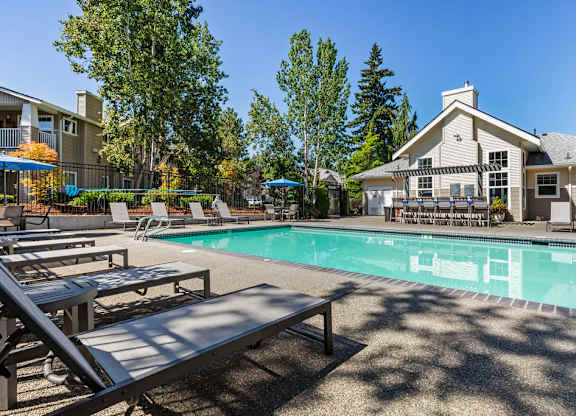 A pool with a bench and a house in the background.