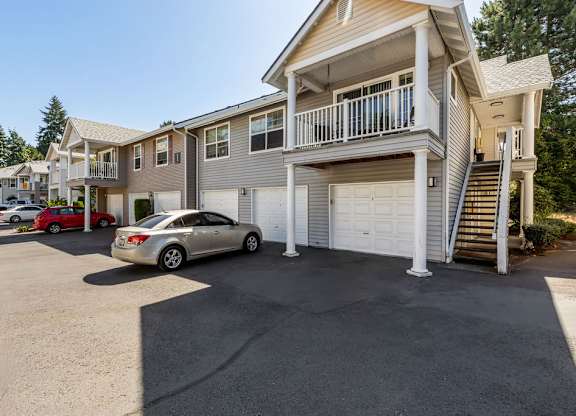 A silver car is parked in a driveway in front of a two-story house.