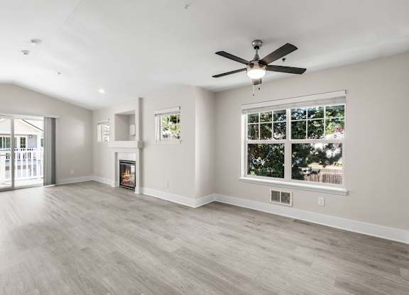 A spacious living room with a fireplace and a ceiling fan.