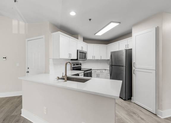 A kitchen with white cabinets and a black refrigerator.