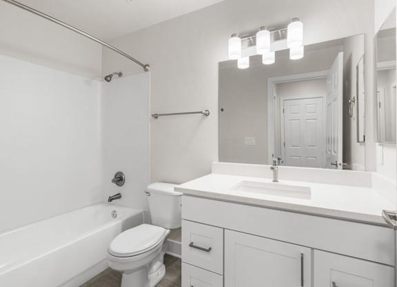 A white bathroom with a toilet, sink, and bathtub.