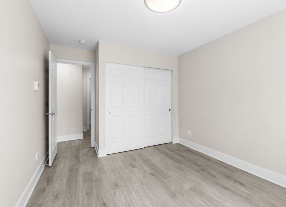 A white door is in the middle of a room with wood flooring.