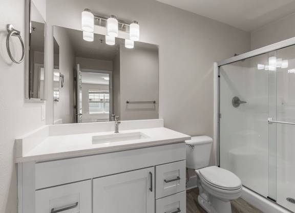 A white bathroom with a sink, toilet, and mirror.