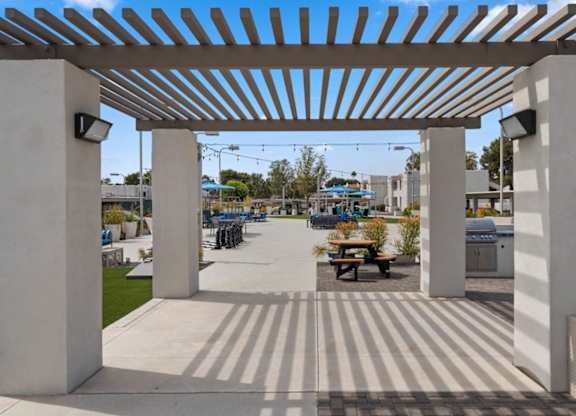 A white pergola with a striped floor and a picnic table underneath.
