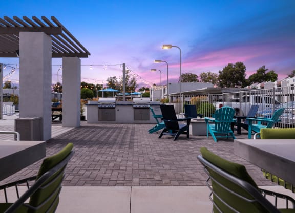 a patio with chairs and a grill at dusk