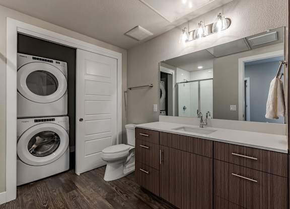 A modern bathroom with a washer and dryer built into the cabinetry.