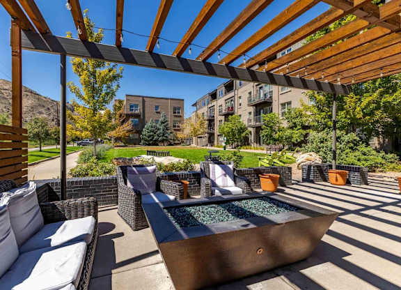 A patio with a hot tub and a wooden pergola.