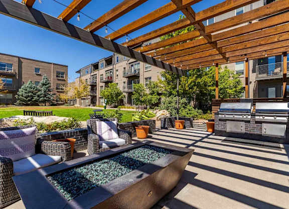 A patio with a hot tub and a wooden pergola.