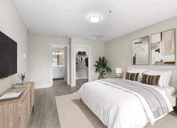A bedroom with a large bed, a wooden nightstand, and a TV on the wall.