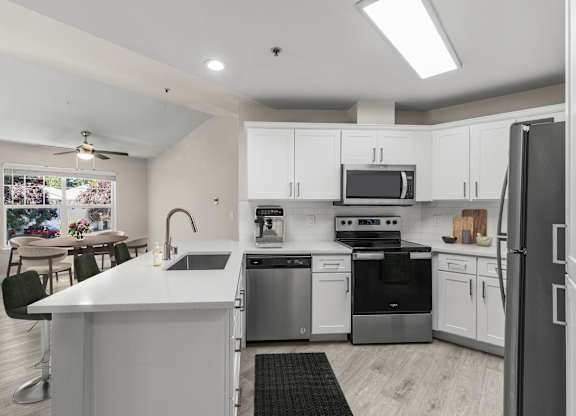 A modern kitchen with white cabinets and stainless steel appliances.