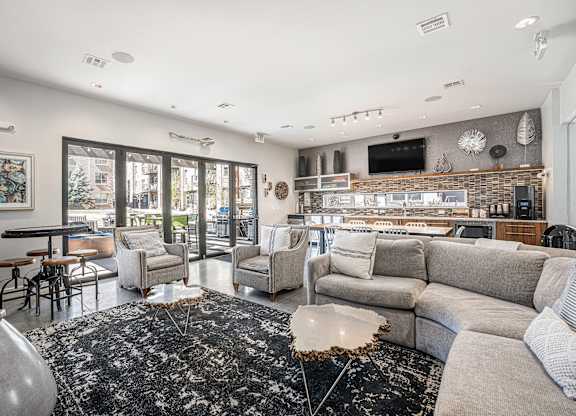 A modern living room with a black and white rug, a grey sofa, and a flat screen TV mounted on the wall.