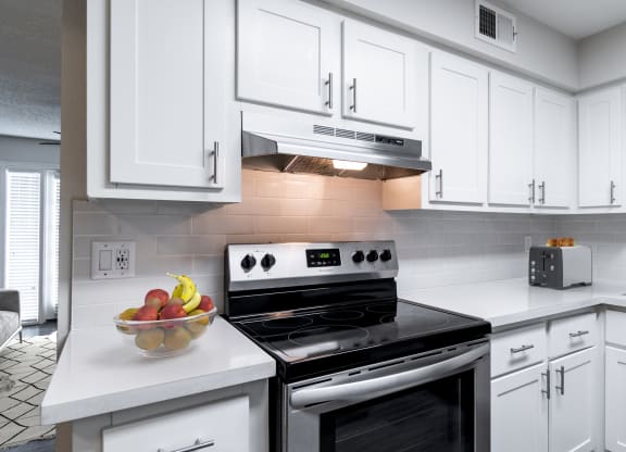 a kitchen with white cabinets and a bowl of fruit on the counter