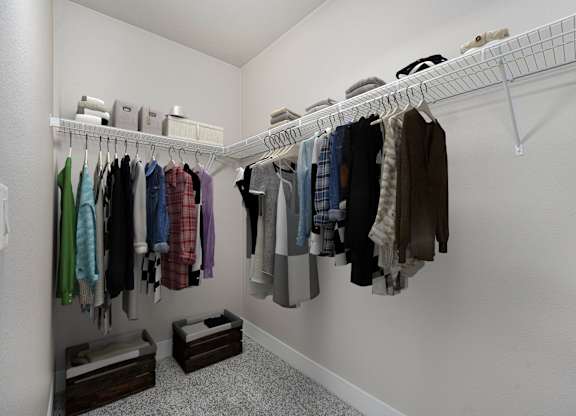 A white closet with clothes hanging on a rail.
