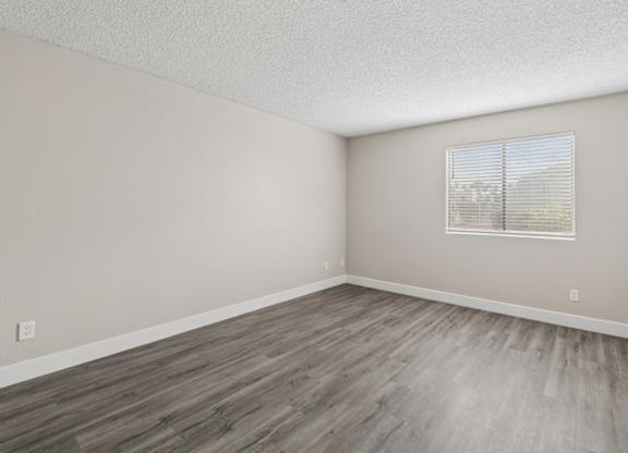 A room with a window and wooden flooring.