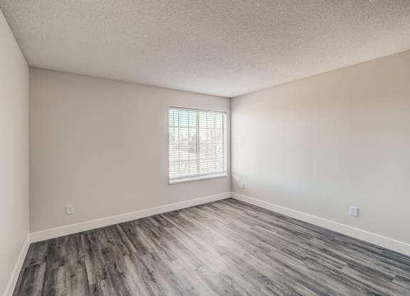 an empty bedroom with hardwood floors and a window