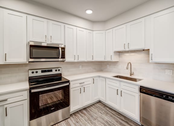 a kitchen with white cabinets and stainless steel appliances