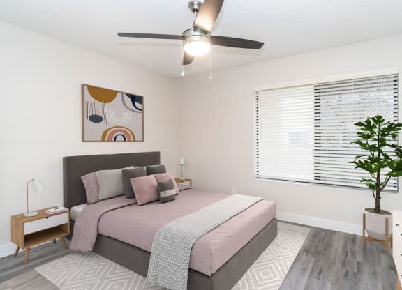 a bedroom with a large window and a ceiling fan