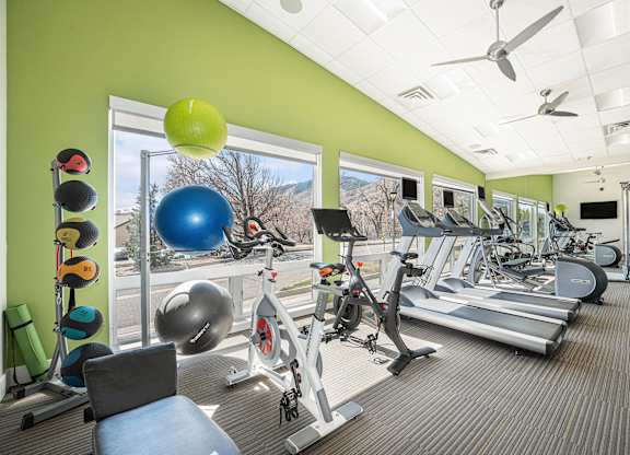 A gym with a variety of equipment including treadmills, exercise balls, and weights.