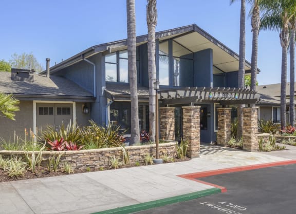 a house with a driveway and palm trees in front of it