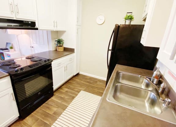 a kitchen with white cabinets and black appliances
