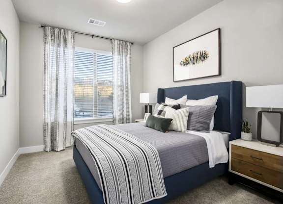 A bedroom with a large bed and a window with curtains.