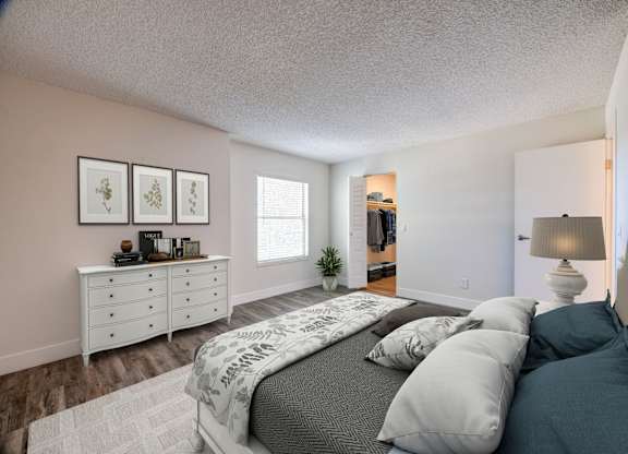 A bedroom with a bed, dresser, and a plant.