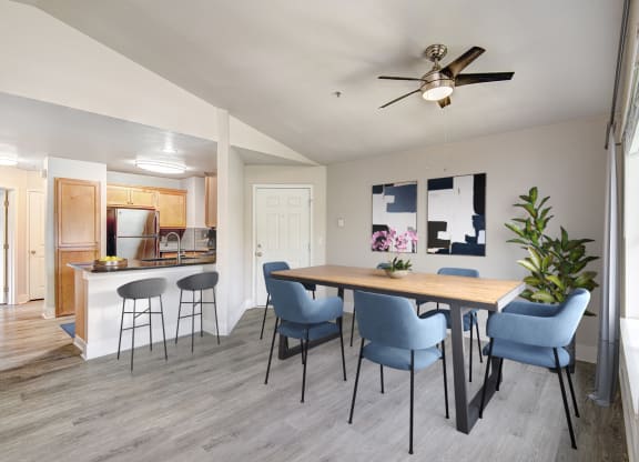 a dining area with a table and chairs and a kitchen in the background