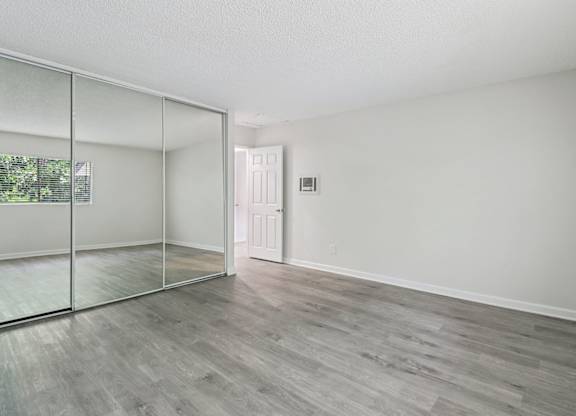 A room with a sliding glass door and wood flooring.
